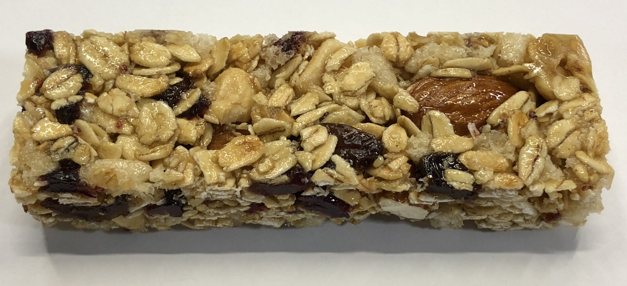 granola bar - pale brown oat flakes, dark fruit, golden brown nuts - on white background