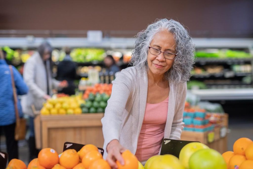 Older woman of colour selecting vegetables from a shop display