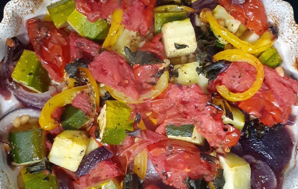 Cooked ratatouille; red, yellow and green vegetables in white flan dish