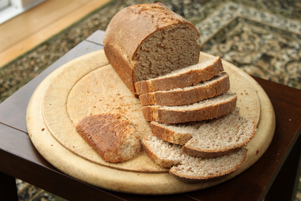 brown wholemeal bread on round breadboard, 5 slices and crust cut