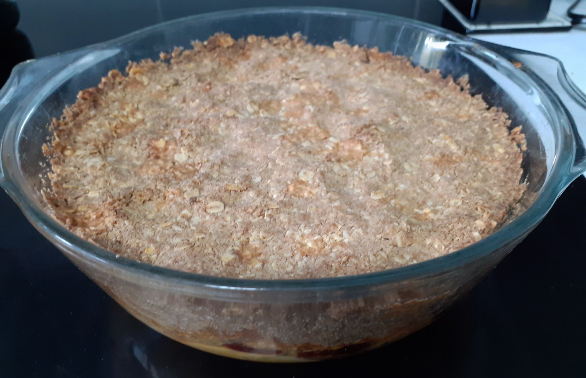 Golden brown cooked crumble in pyrex glass bowl - background terracotta and white