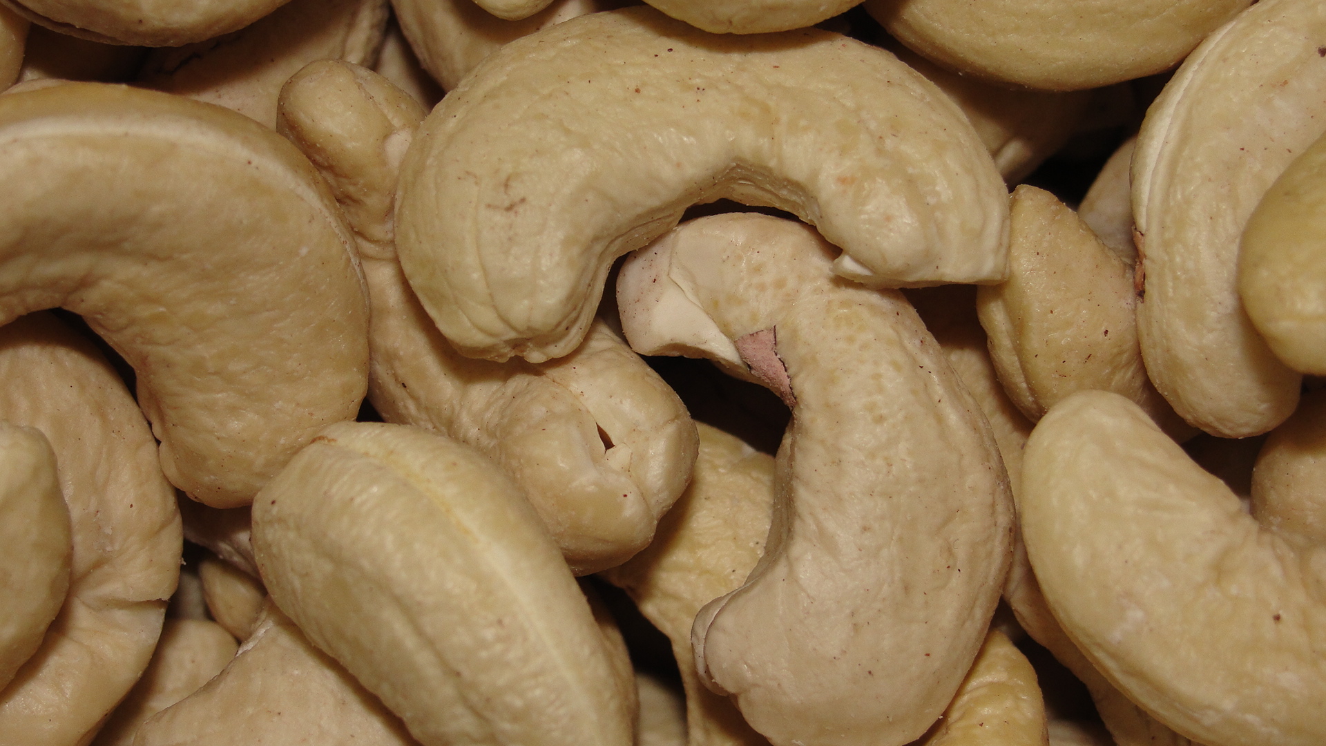close-up of shelled crescent-shaped cashews, light brown colour