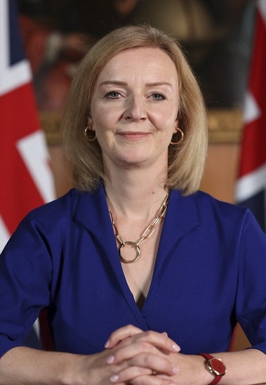Liz Truss in blue suit, backed by Union Flags