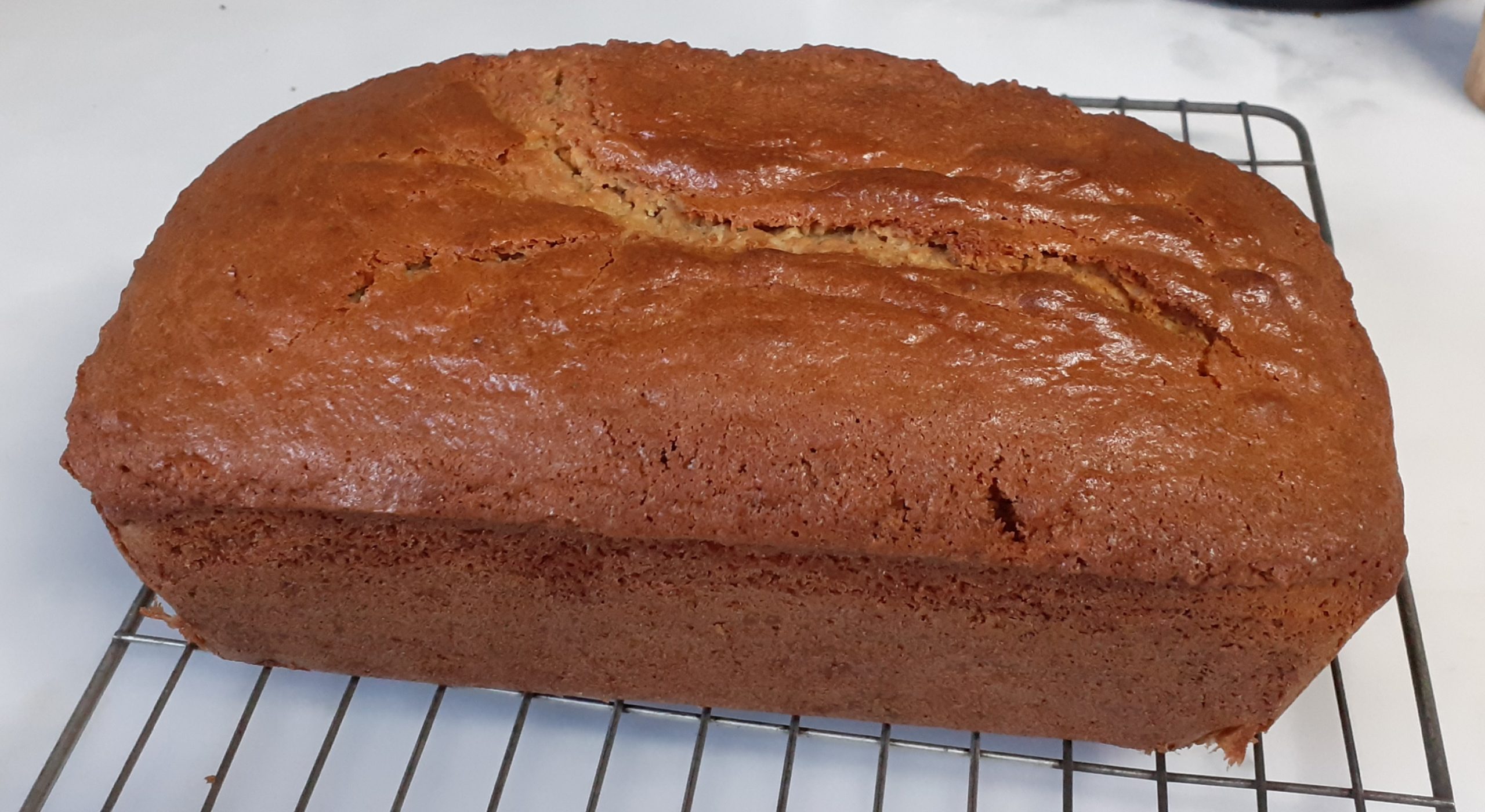 Golden brown loaf cake on wire cooling rack with white background