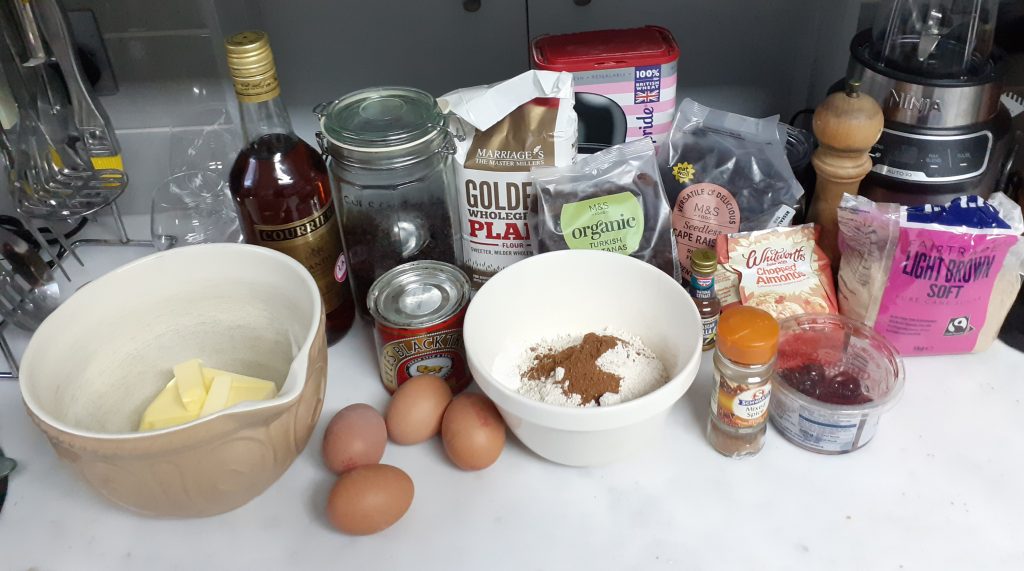 All the ingredients for Christmas Cake - on white worktop with grey background